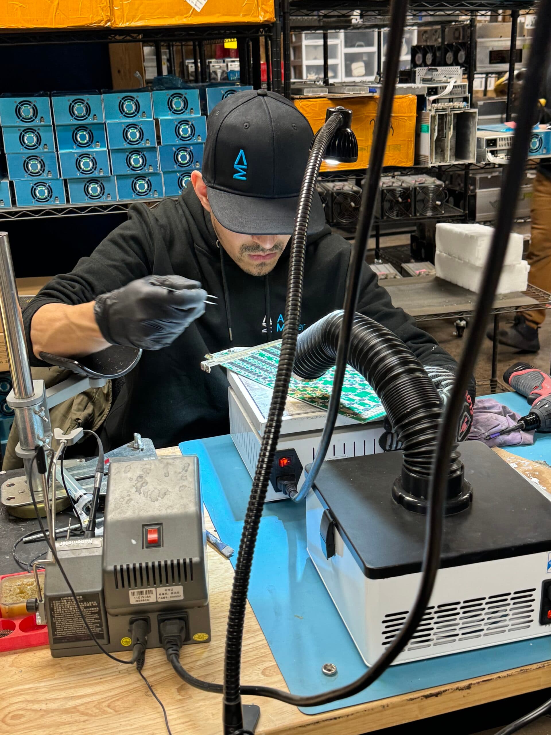 ASIC Master technician performing hash board repair at the workbench